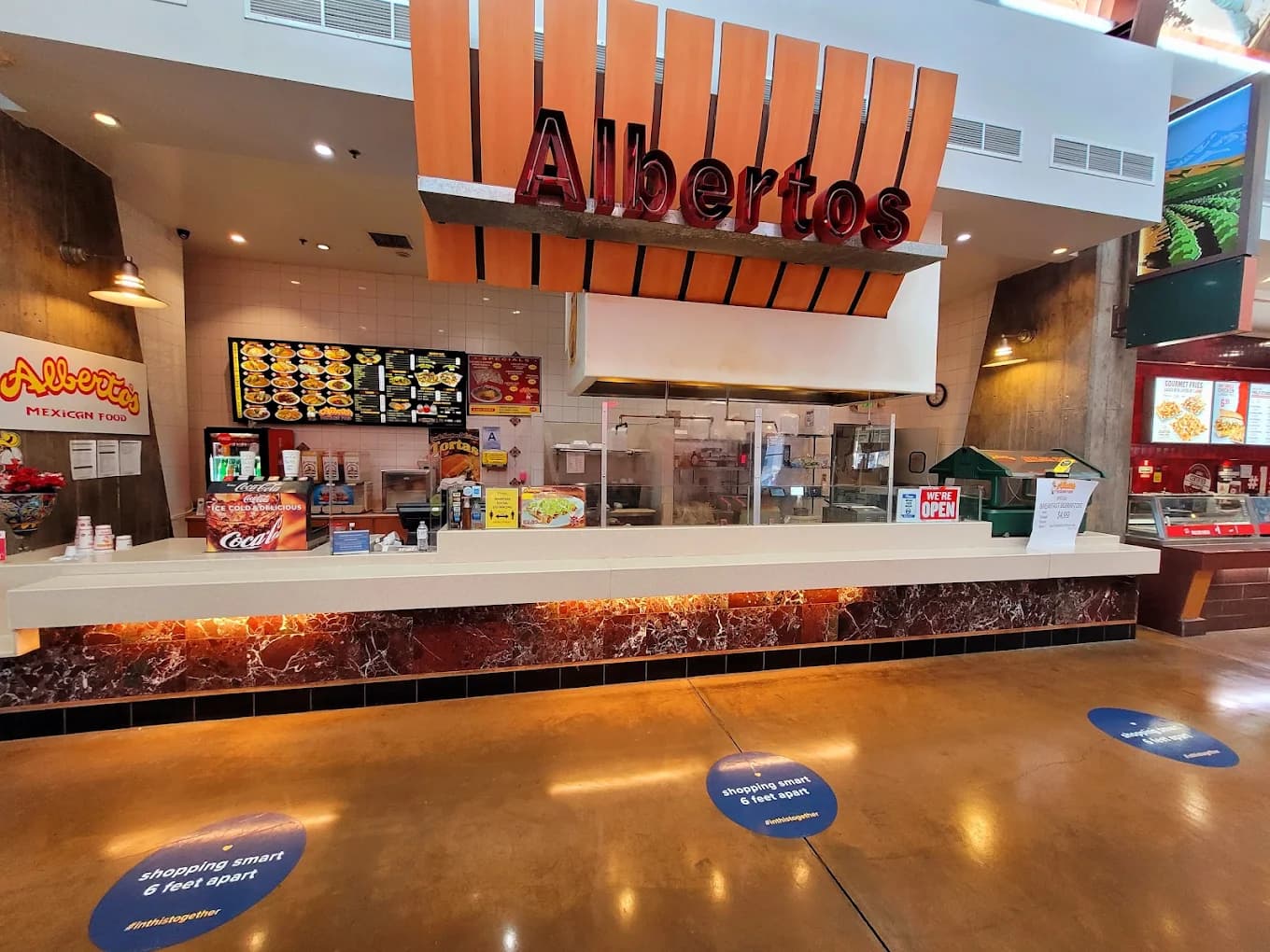 Food court counter at Albertos Mexican Food with a large orange Albertos sign and photo menu board