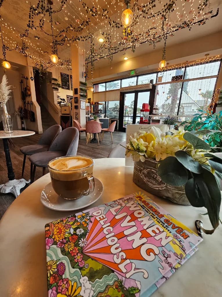 Latte on a marble table at Apartment Cafe with string lights and hanging greenery overhead