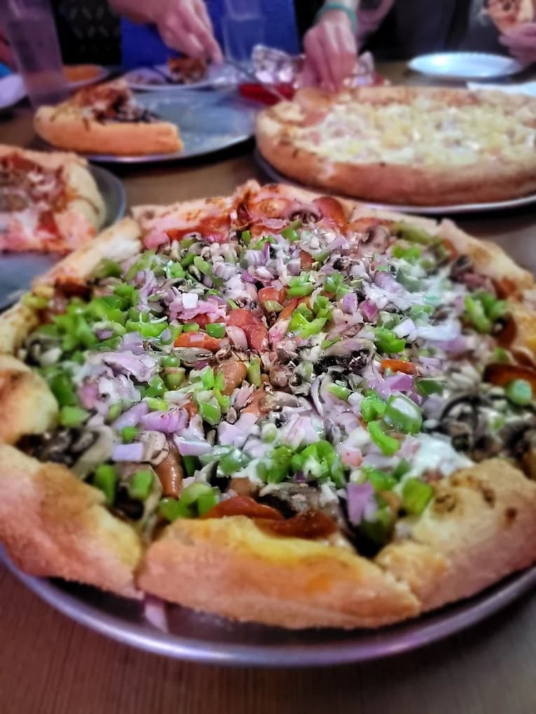 Pizza topped with green peppers, onions and mushrooms on a metal tray at B & J's Pizza & Sandwiches