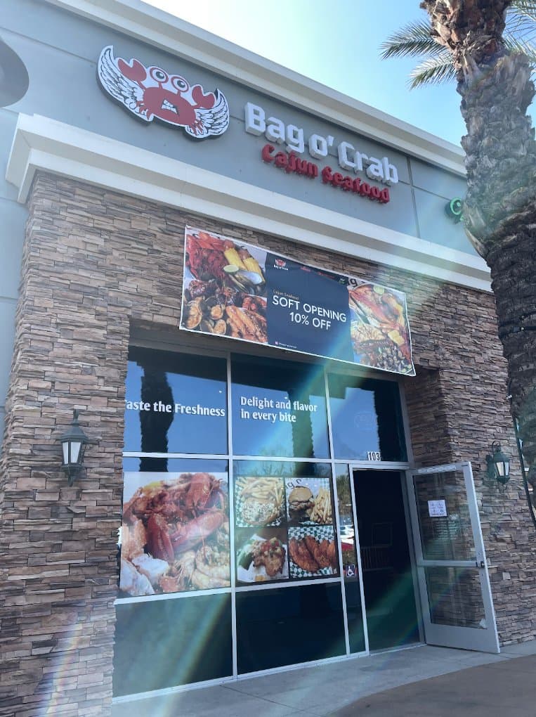Storefront of Bag O' Crab with a winged crab logo and seafood photos in the windows