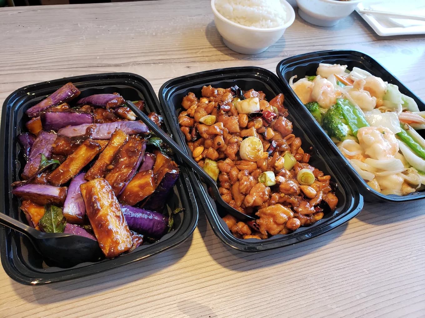 Takeout trays of eggplant, kung pao chicken and shrimp with vegetables from Bamboo Kitchen Chinese Cuisine