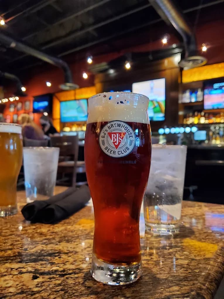 Pint of amber beer in a Beer Club glass on a granite bar table at BJ's Restaurant & Brewhouse
