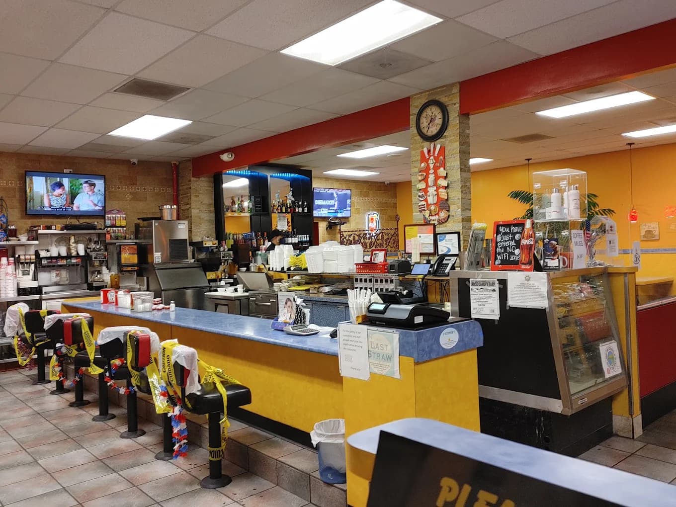 Yellow and blue counter with stools, wall clock and pastry case inside Brandon's Diner