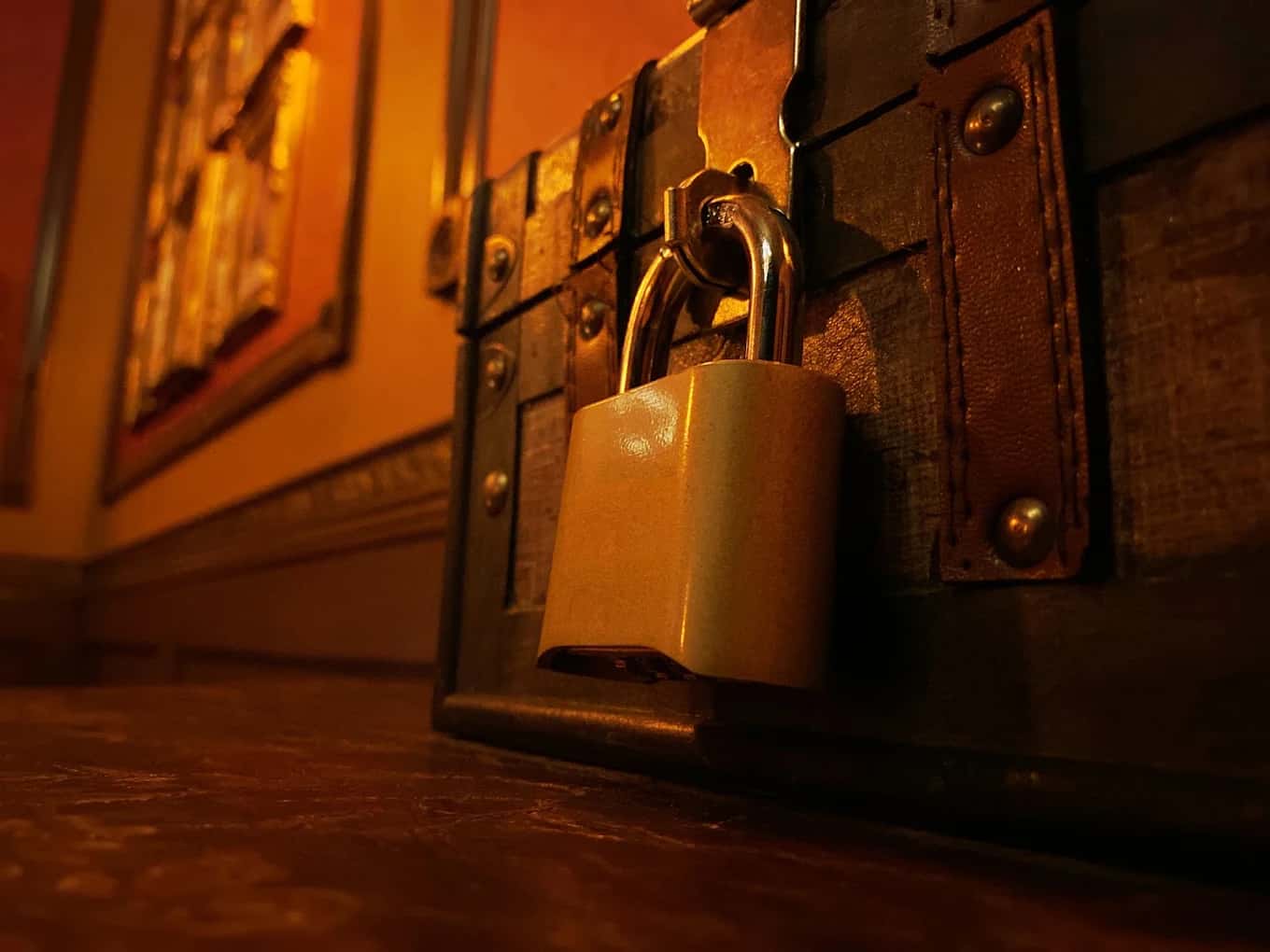 Close-up of a padlock on a riveted wooden chest in a dimly lit room at Breaking Point Escape Rooms