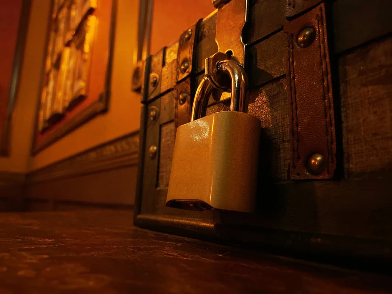 Close-up of a padlock on a riveted wooden chest in a dimly lit room at Breaking Point Escape Rooms