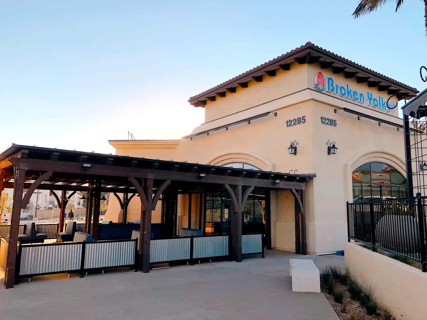 Stucco exterior of Broken Yolk Cafe with a covered wooden patio and rooftop sign