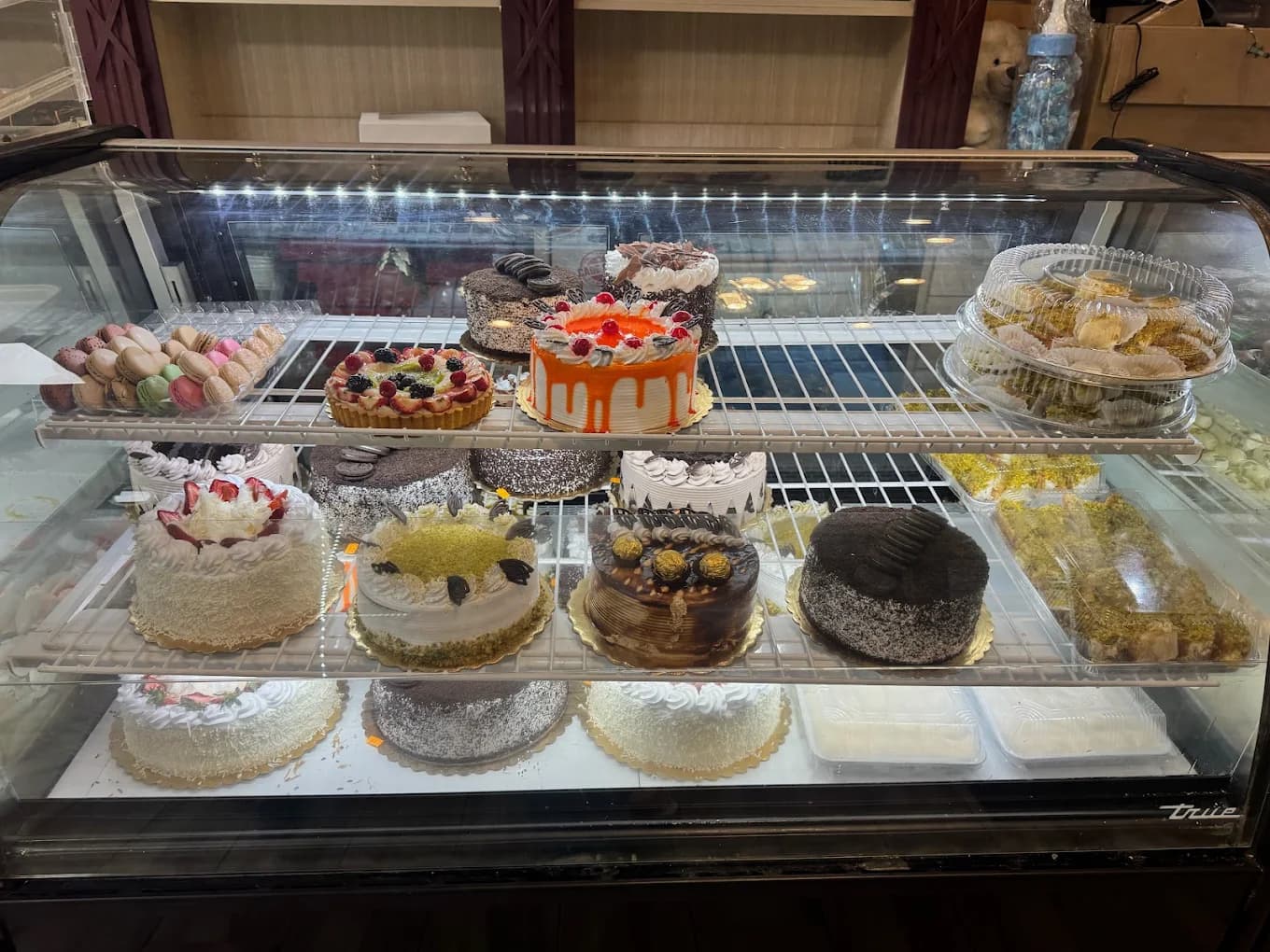 Glass display case filled with decorated cakes, macarons and a fruit tart at Caesar's Pastry