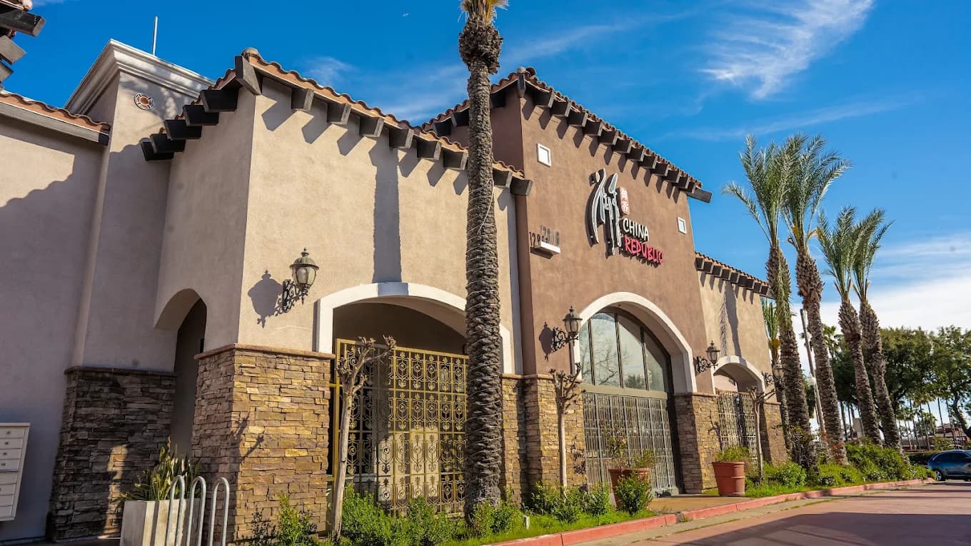 Exterior of China Republic with arched windows, stone-clad columns, a tile roof and palm trees