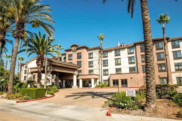 Country Inn & Suites by Radisson exterior, a tan four-story hotel framed by tall palm trees