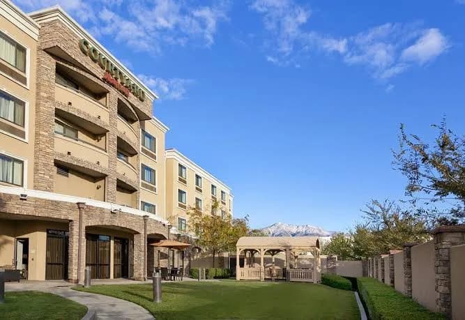 The Courtyard hotel seen from its lawn, a gazebo and patio in front and a snow-topped peak rising behind the building