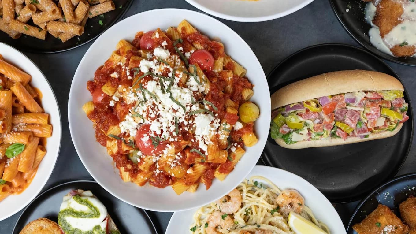 Overhead spread of pasta dishes, a loaded sub sandwich and fried bites from Creators' Kitchen as Seen on TikTok