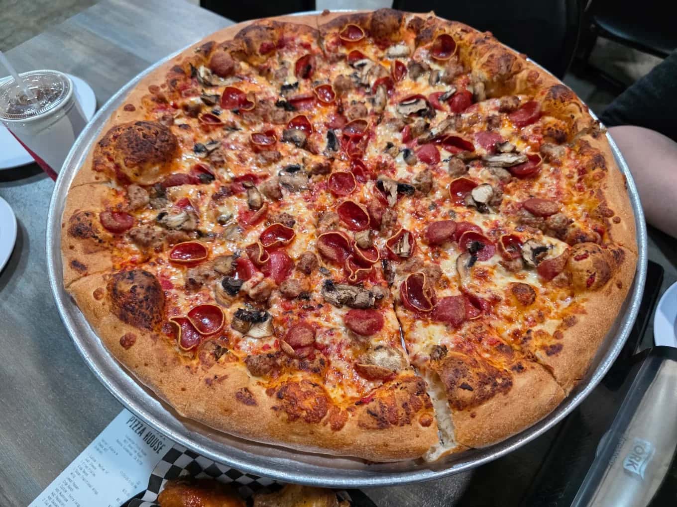 Pepperoni, sausage and mushroom pizza on a metal tray at Cucamonga Pizza House