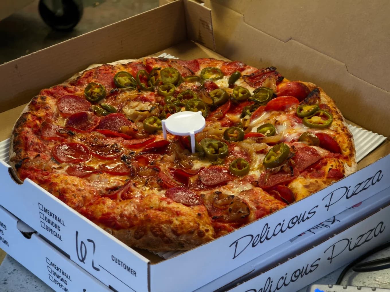 Pepperoni and jalapeno pizza in an open takeout box from Dalia's Pizza