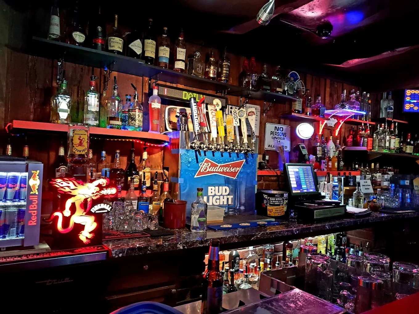 Back bar with liquor shelves, beer taps and neon signs at Deane's Bar and Thrill