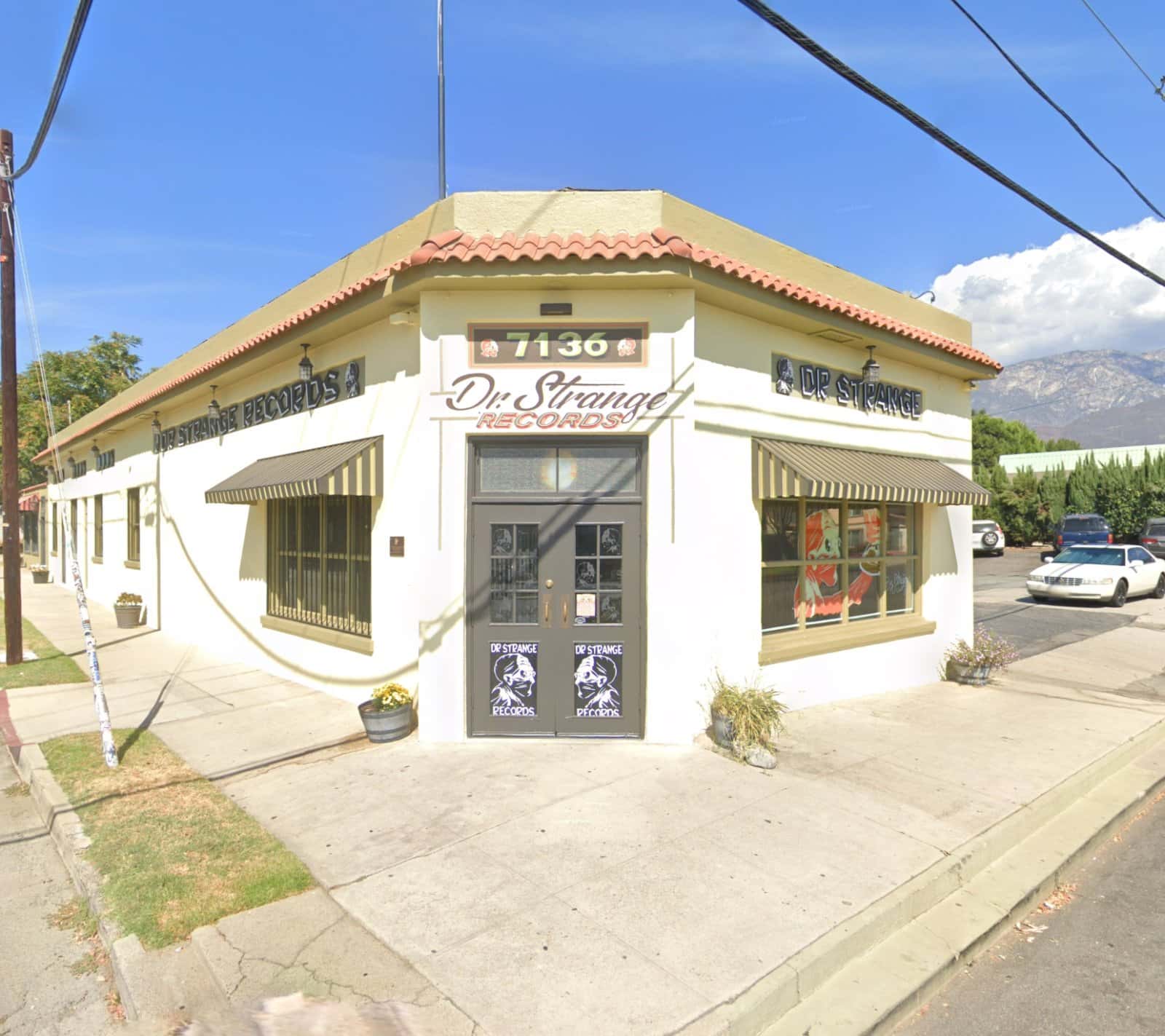 Corner storefront of Dr. Strange Records with striped awnings, tile roof and painted signage