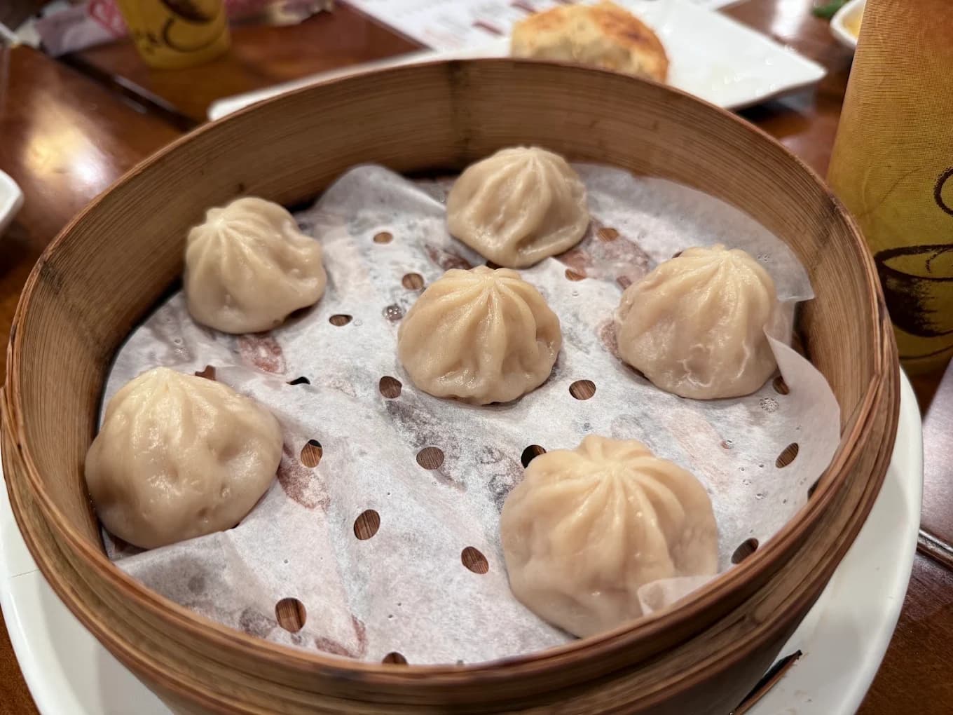 Six soup dumplings in a bamboo steamer basket at Dumpling Master