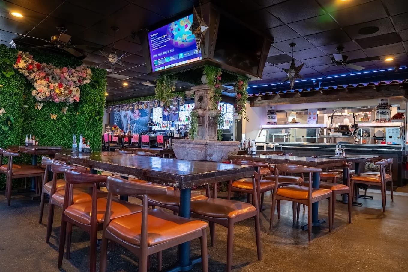 Dining room at El Cerrito Mexican Grill and Bar with a stone fountain, greenery wall and wooden tables