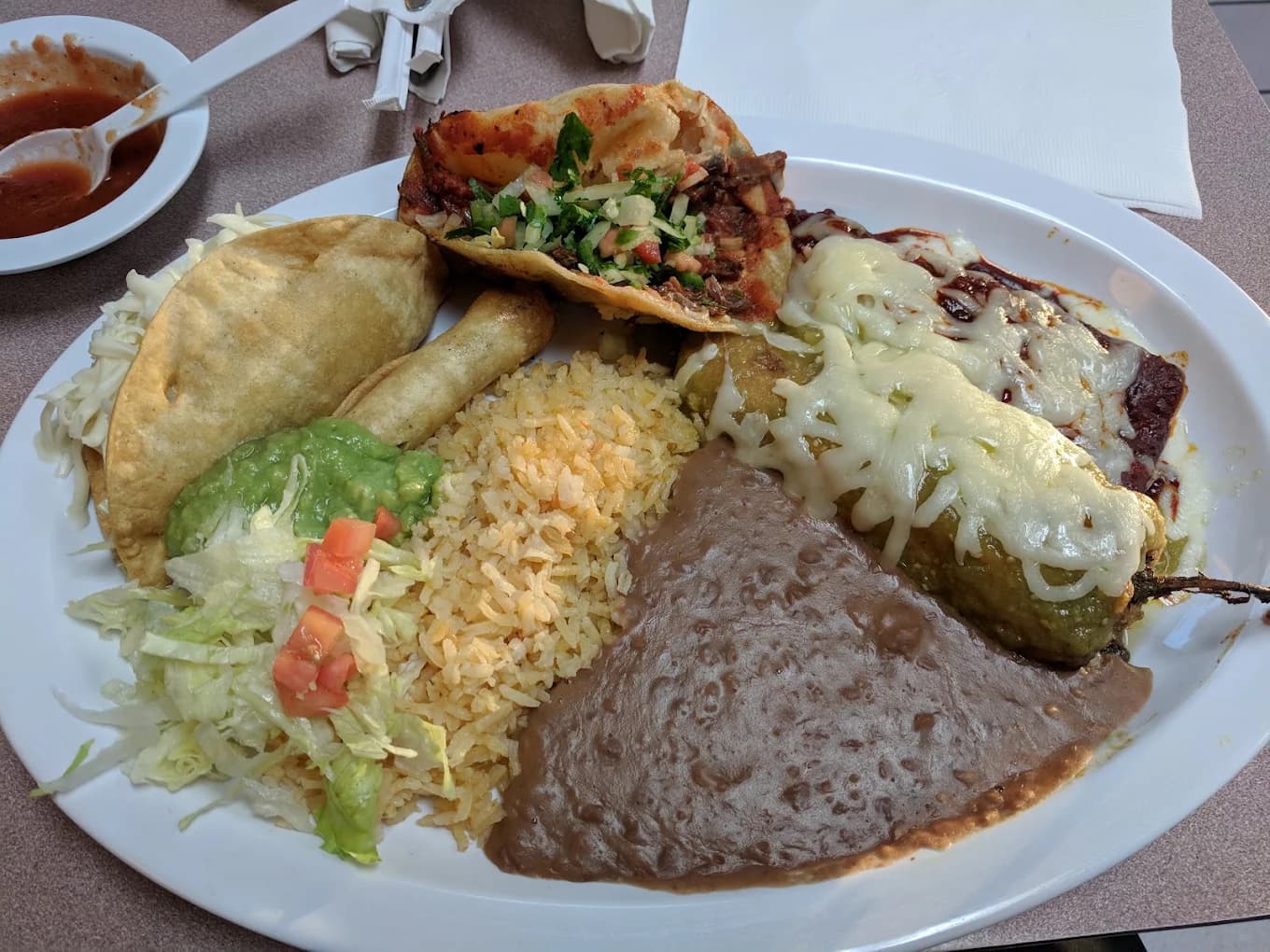 Combination plate with taco, chile relleno, rice, beans and guacamole at El Patron Authentic Mexican Food