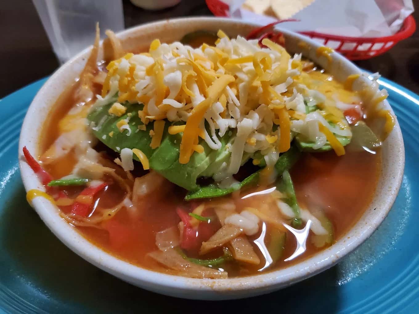 Bowl of tortilla soup topped with avocado and shredded cheese at El Perico Ranchero