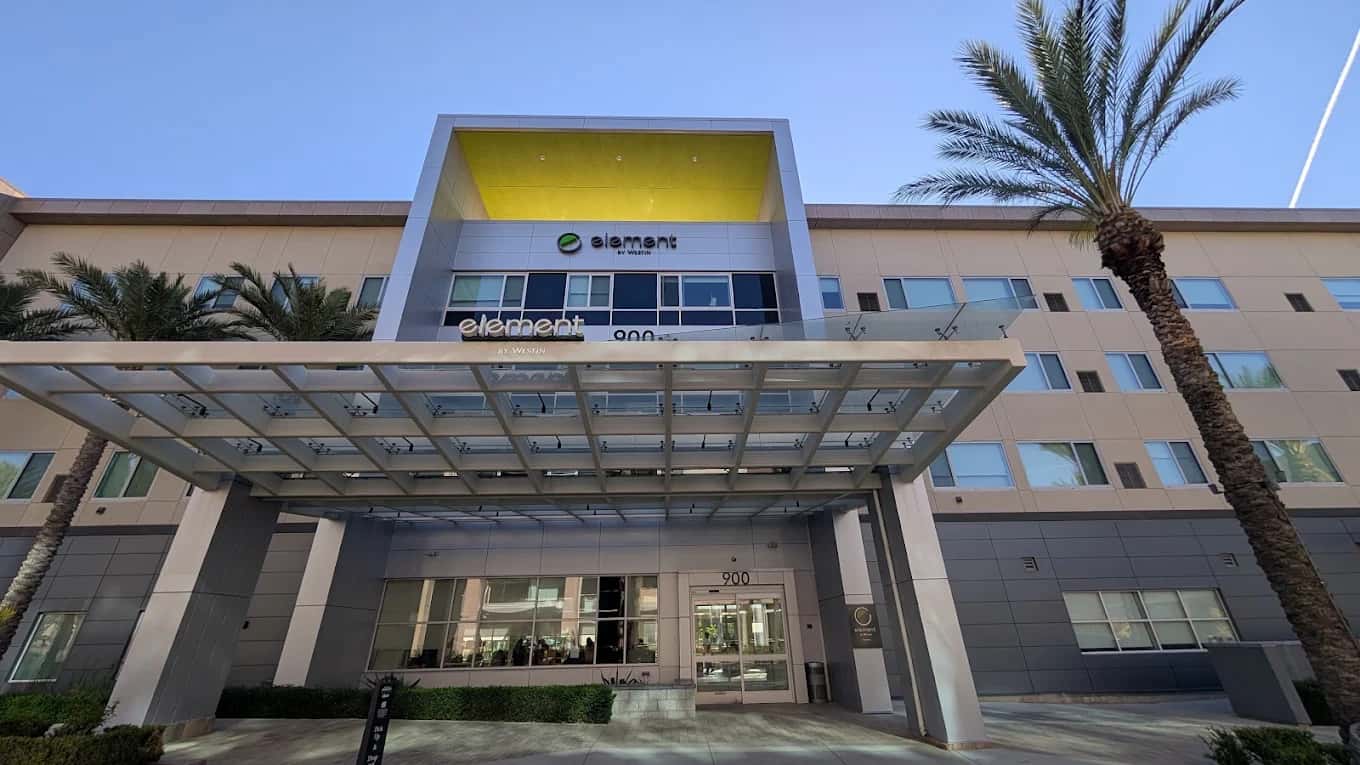 Front entrance and canopy of Element Ontario with palm trees and a yellow accent above the sign