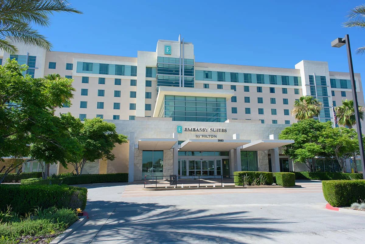 Front entrance and hotel tower of Embassy Suites by Hilton Ontario Airport under a clear sky
