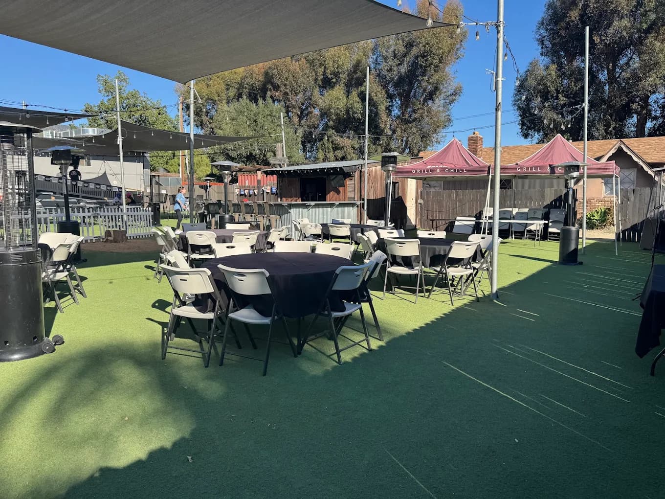 Outdoor patio with round tables, shade sails and string lights at The Etiwanda Roadhouse
