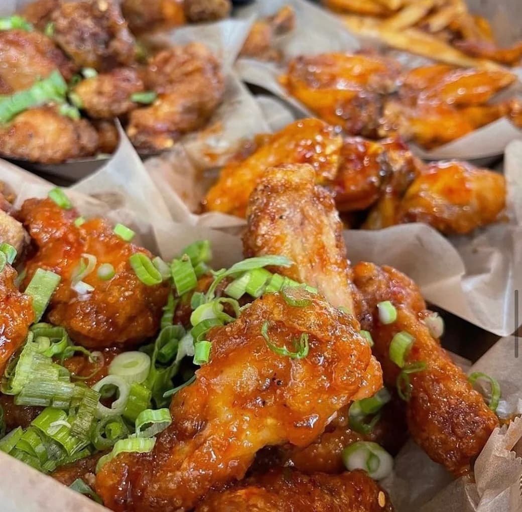Trays of sauced chicken wings topped with green onions at Fire Wings
