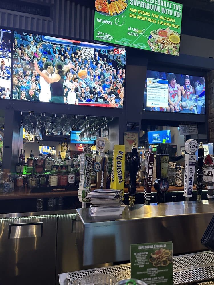 Bar with beer taps and TVs showing basketball at 4th & Mill