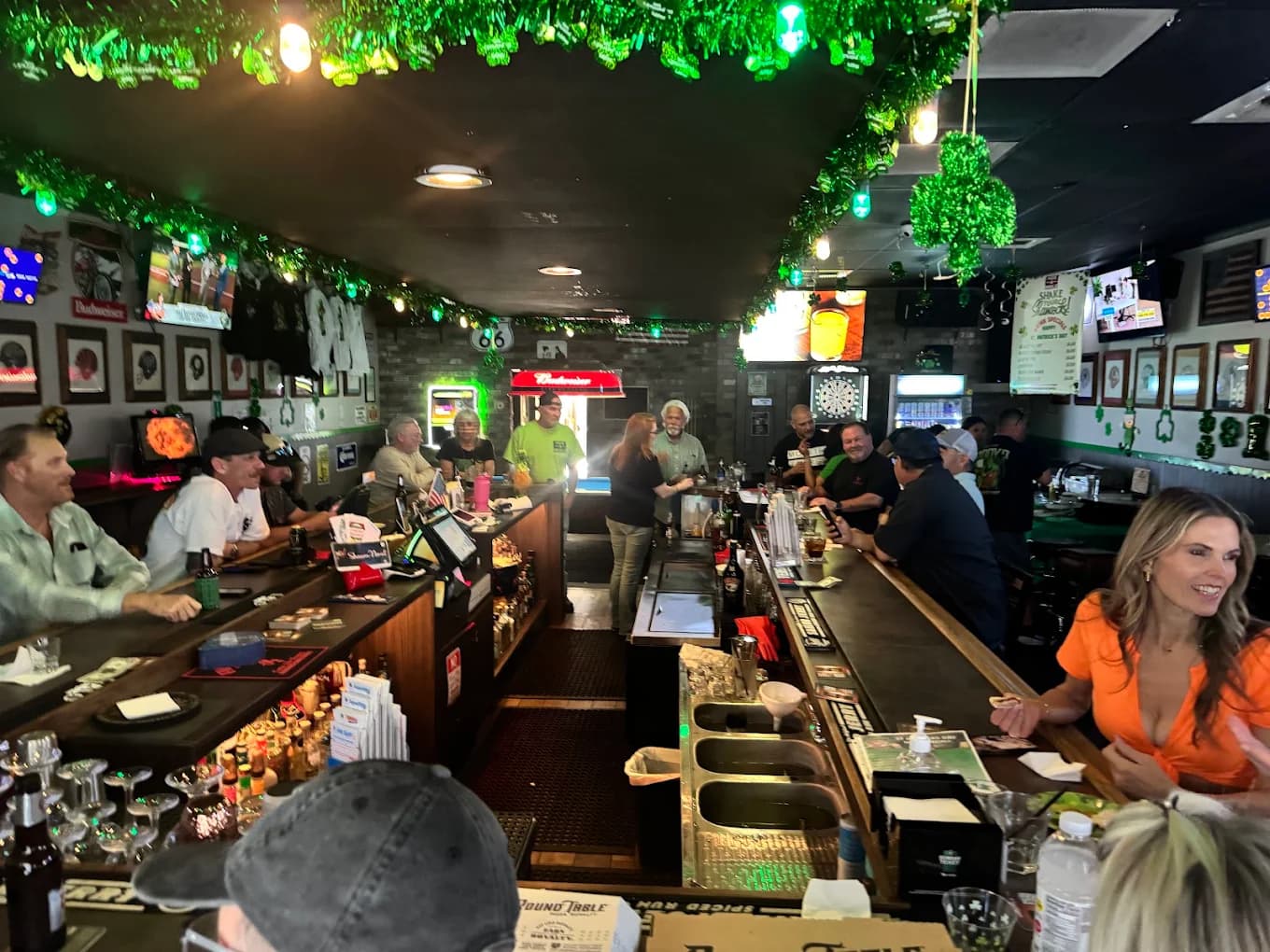 Crowded bar at Hide-A-While Bar & Lounge decorated with green garland, TVs and framed photos