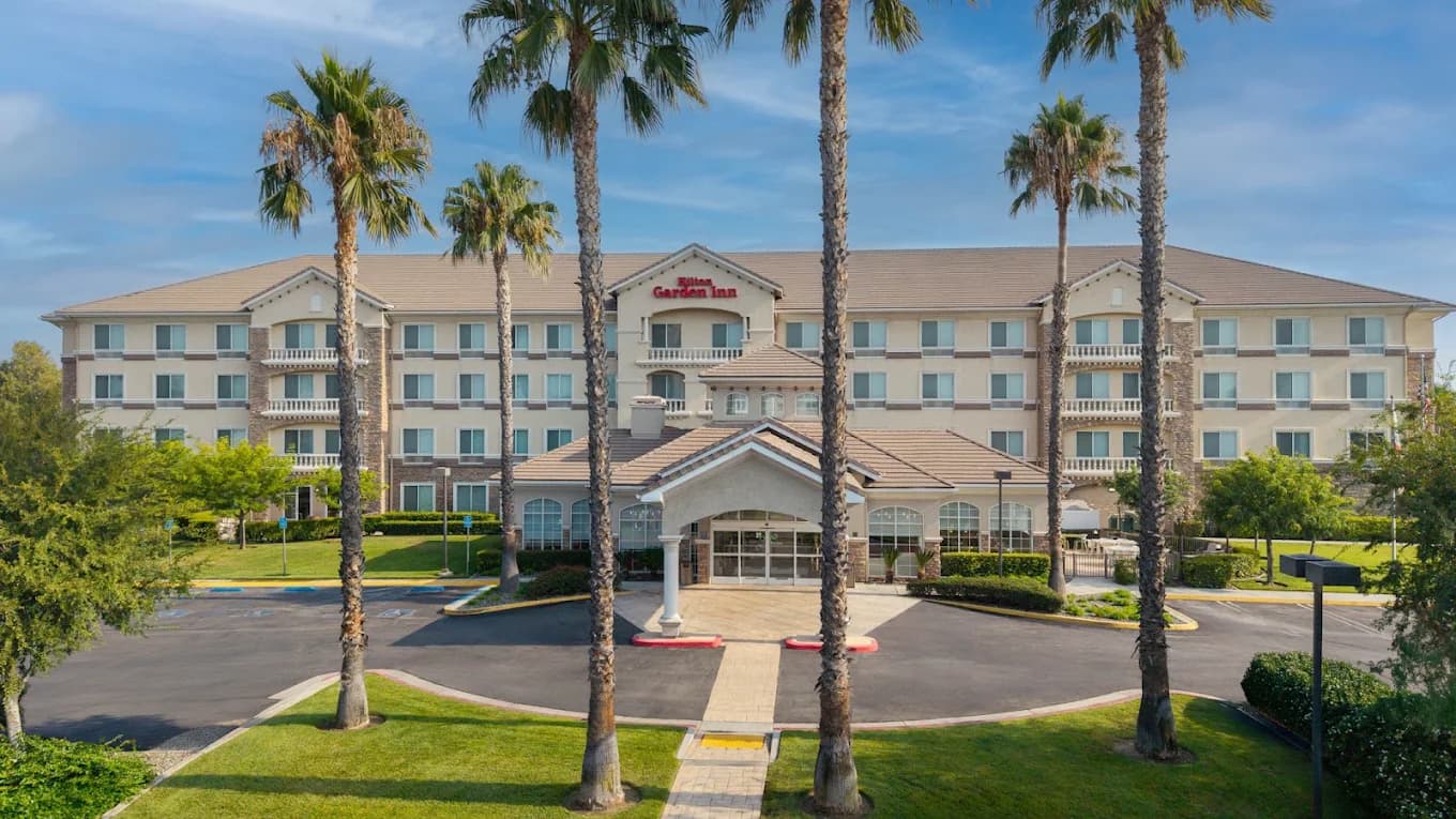 Palm-lined driveway and front entrance of the four-story Hilton Garden Inn Ontario/Rancho Cucamonga