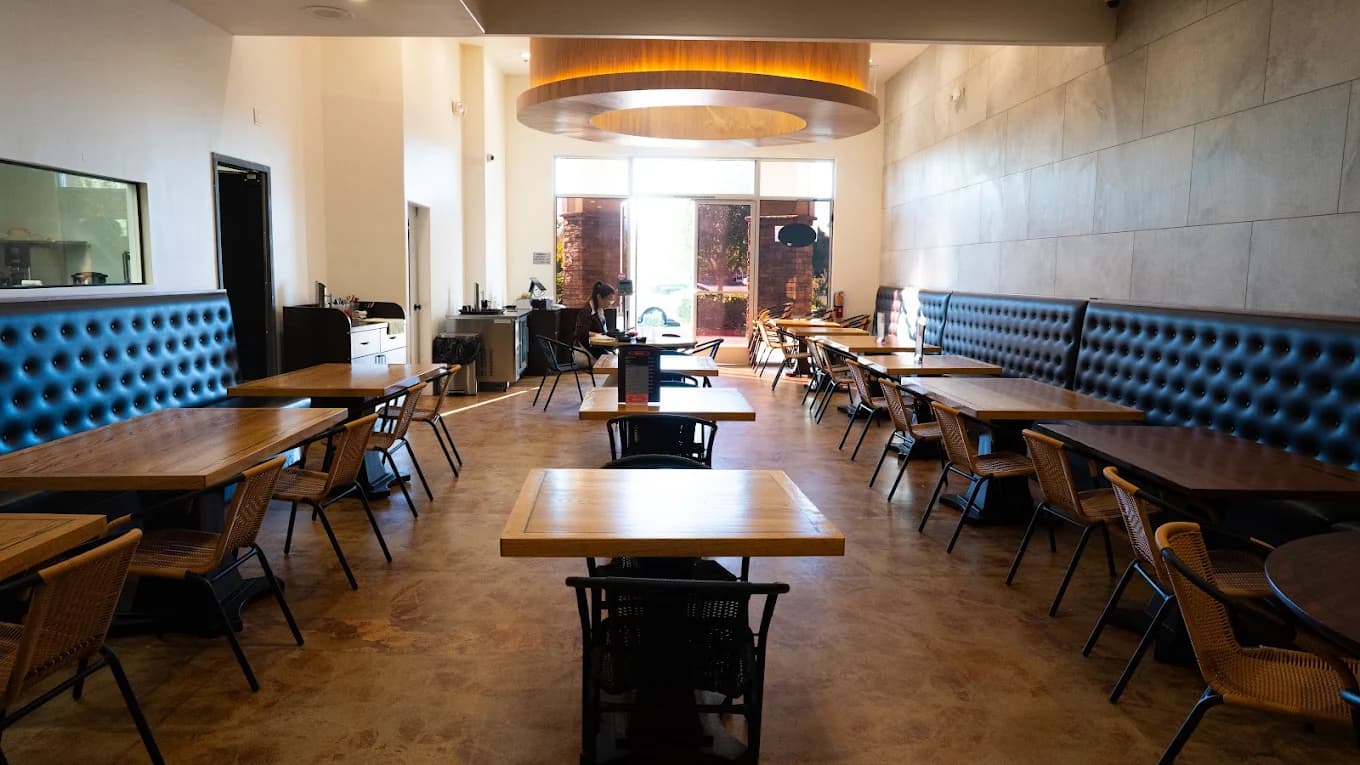 Dining room at Hop Haus 成都食府 with wooden tables, tufted blue banquettes and a round ceiling light