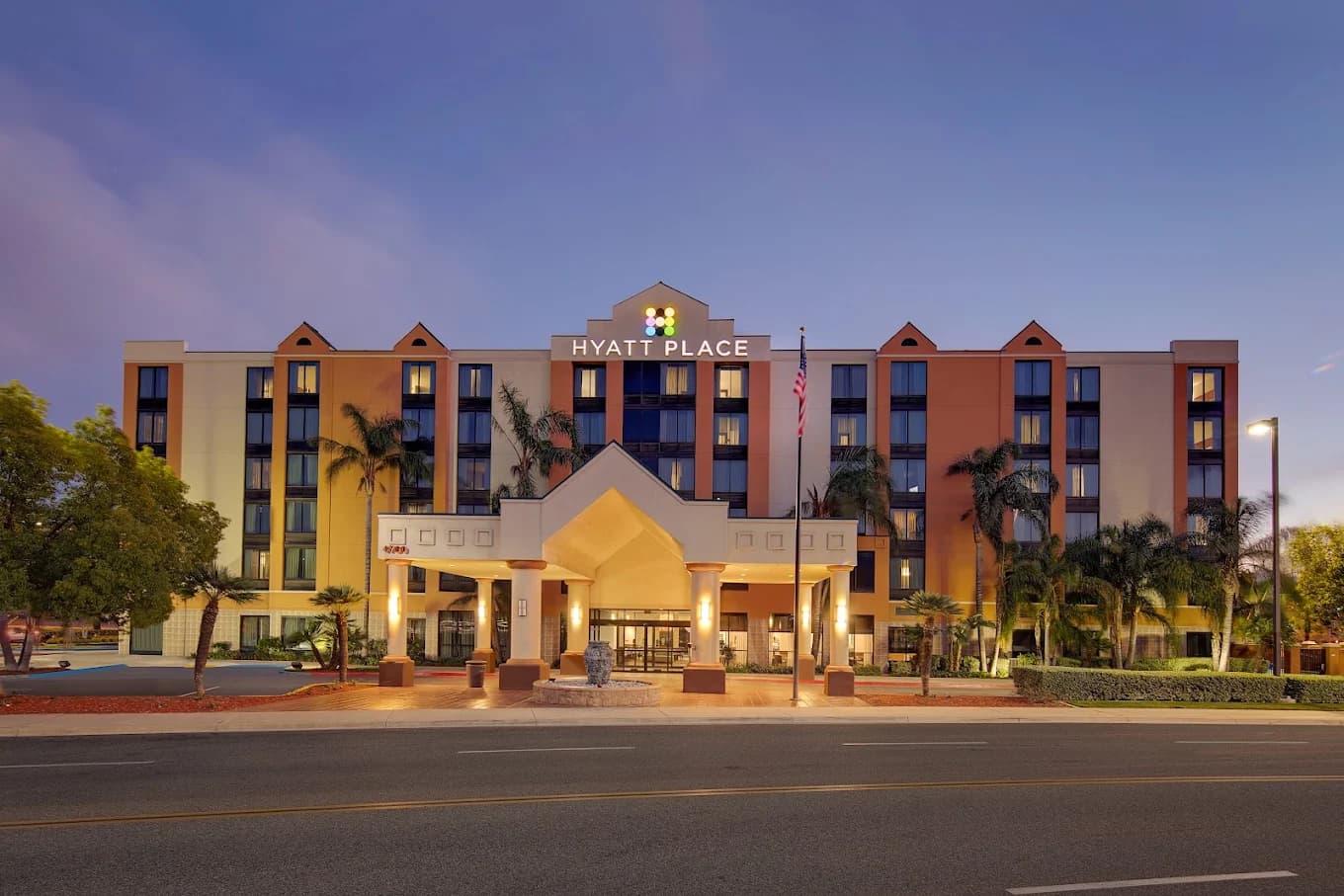 Front entrance of the Hyatt Place Ontario/Rancho Cucamonga at dusk, with its rooftop sign and pillared drive-up canopy