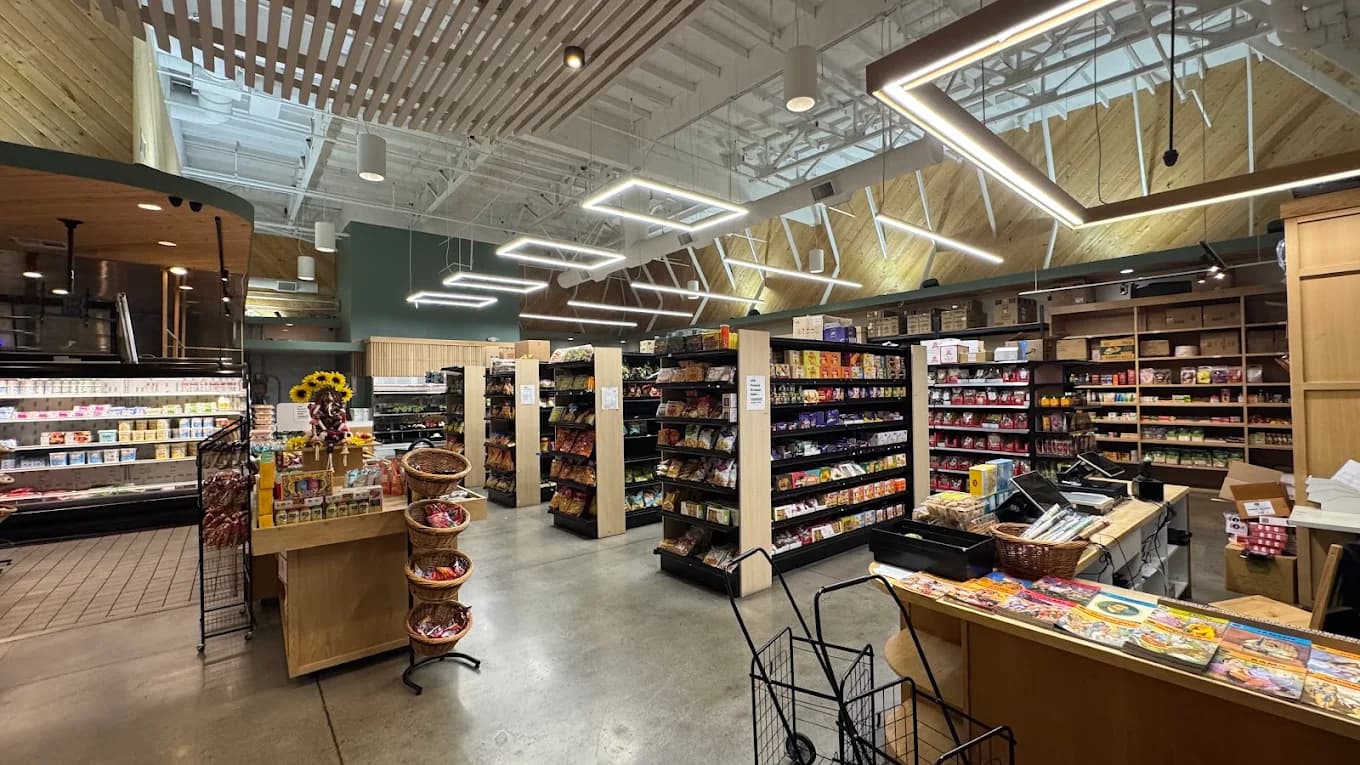 Grocery aisles with packaged foods, baskets and a checkout counter at IBB - India Bites and Bazar
