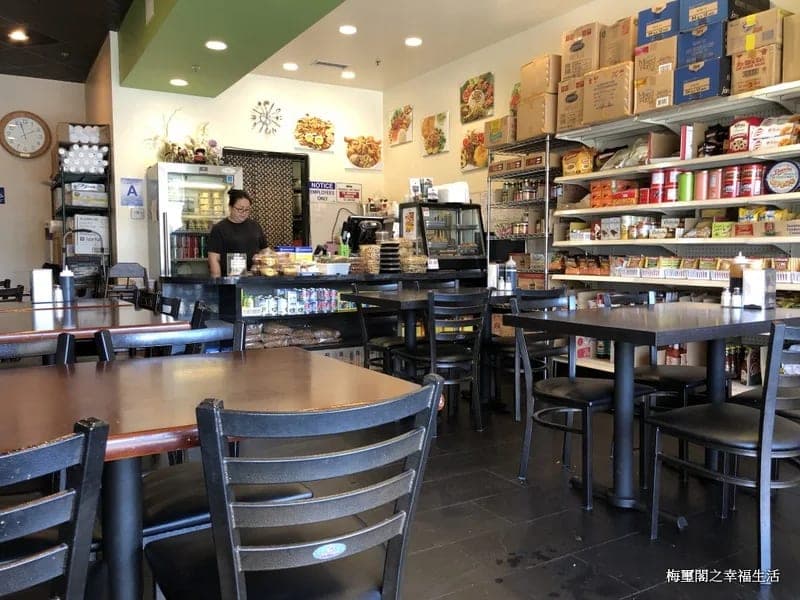 The dining room at Java Bistro, tables and chairs facing a counter with a pastry case and shelves of packaged goods