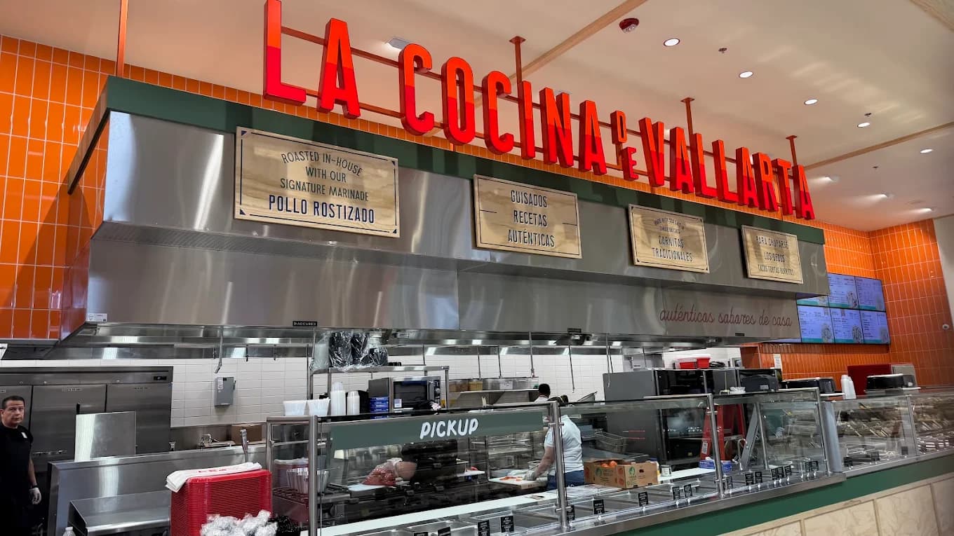 Lit red sign and pickup counter at La Cocina Vallarta with wooden menu boards and orange tile