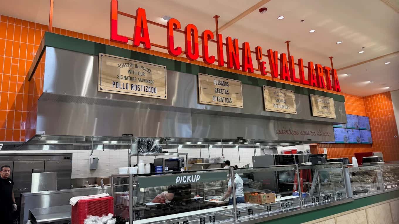 Lit red sign and pickup counter at La Cocina Vallarta with wooden menu boards and orange tile