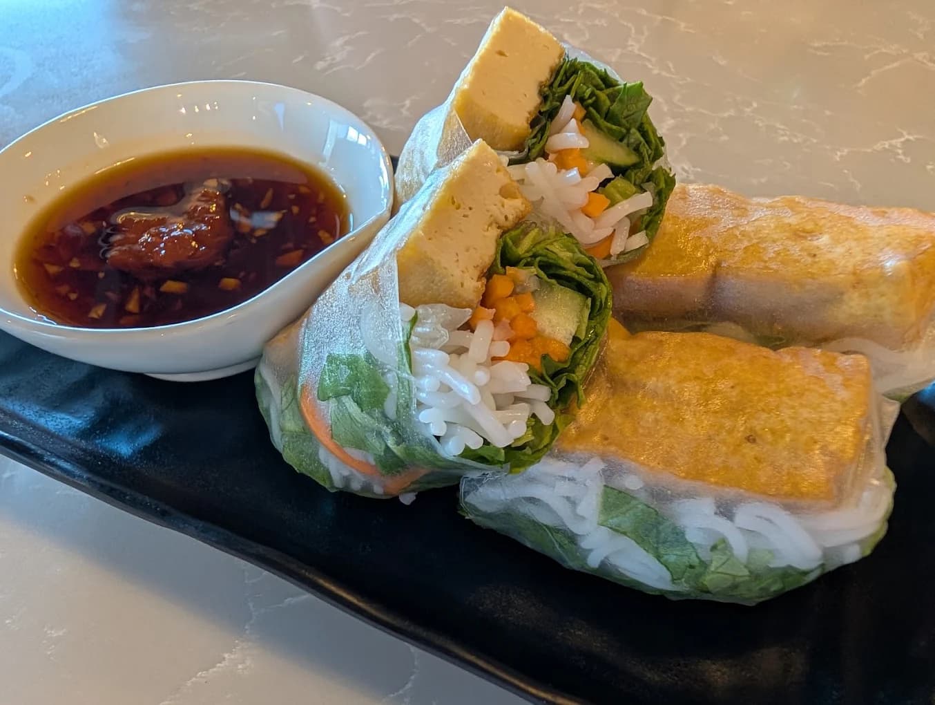 Tofu spring rolls with rice noodles and lettuce beside dipping sauce at Lantern Vietnamese Kitchen