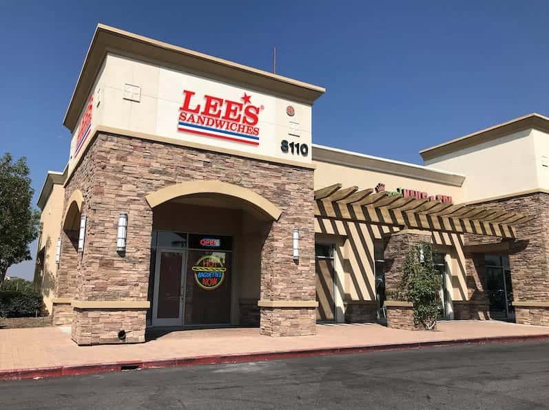 The Lee's Sandwiches storefront, a stone-faced corner building with an arched entry under the red sign