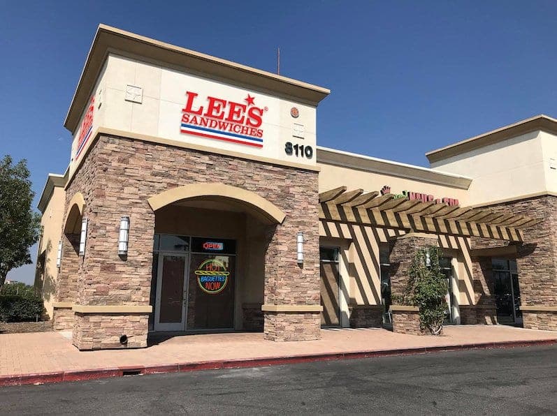The Lee's Sandwiches storefront, a stone-faced corner building with an arched entry under the red sign