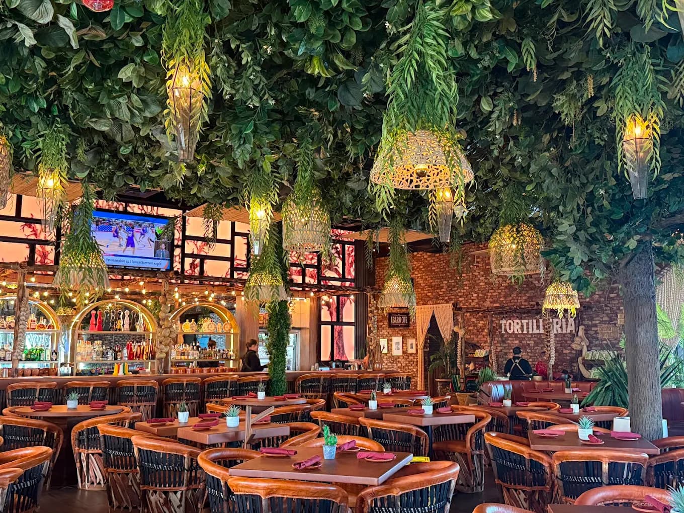 Dining room at Los Amores de Julia with hanging greenery, lanterns, leather chairs and a bar