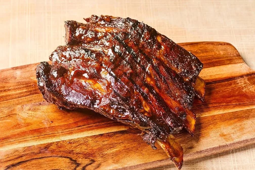 Rack of sauced barbecue ribs on a wooden cutting board at Lucille's Smokehouse Bar-B-Que