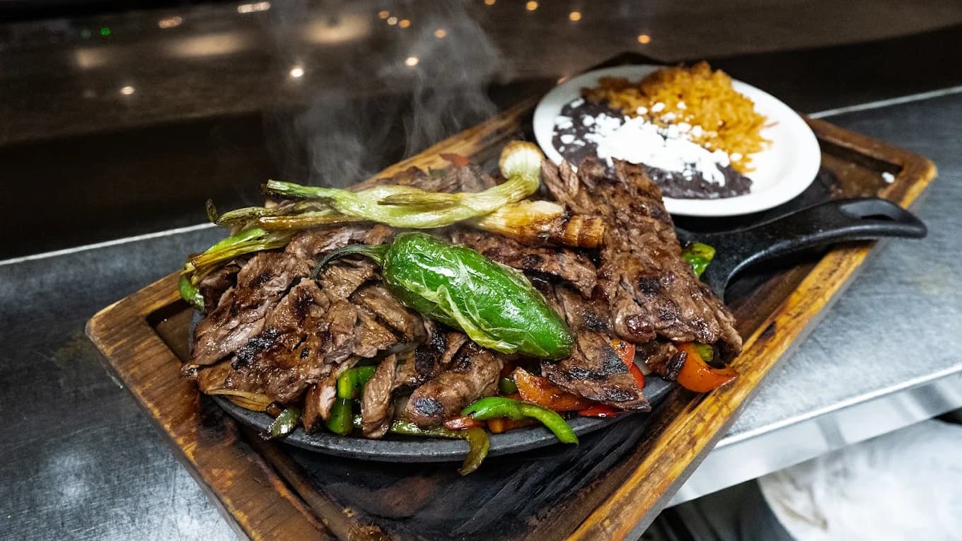 Steaming carne asada with grilled peppers and a side of rice and beans at Luxe Kitchen & Cantina