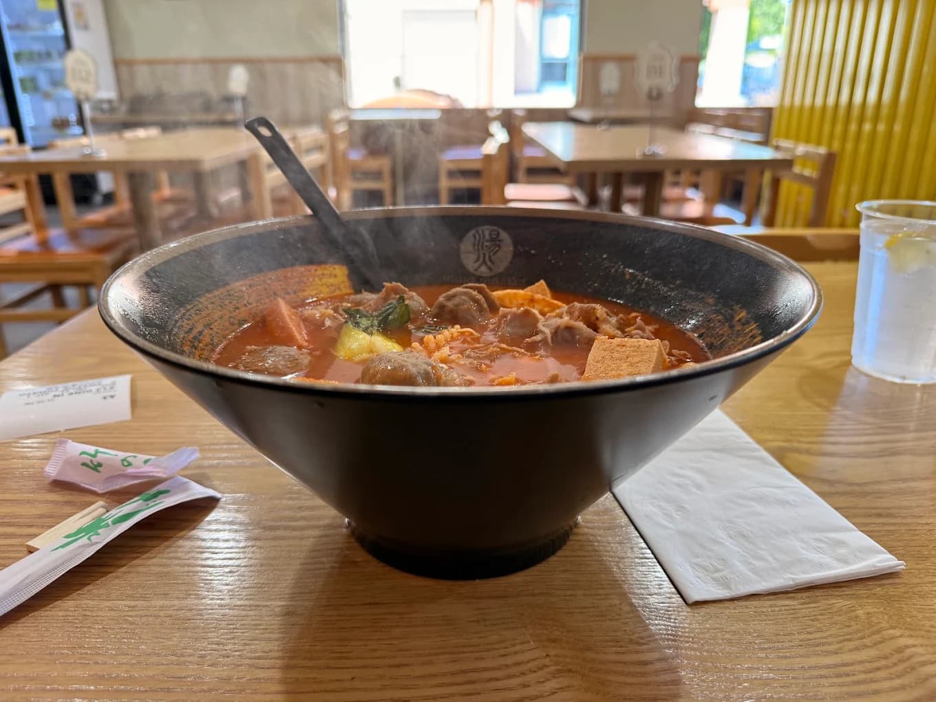 Large steaming bowl of red broth with meatballs and tofu in the dining room at Mala Master Spicy House