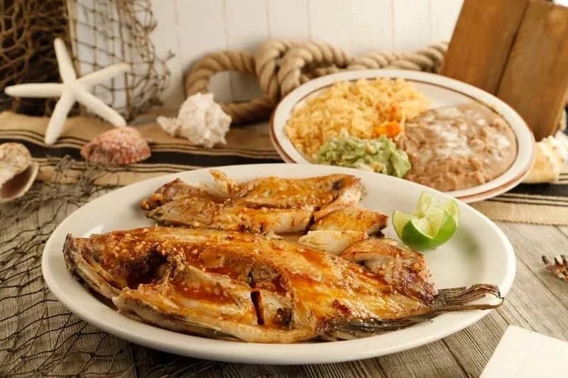 Grilled whole fish with lime beside a plate of rice, beans and guacamole at Mexico Lindo