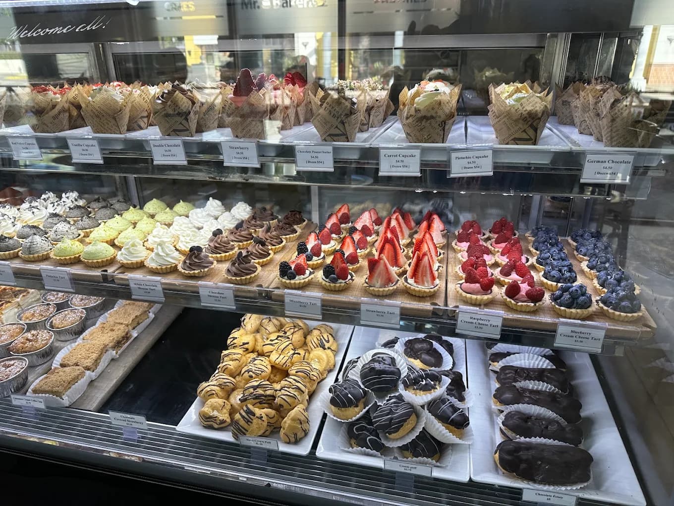 Display case of cupcakes, fruit tarts, cream puffs and eclairs at Mr. Baker Bakery & Cafe