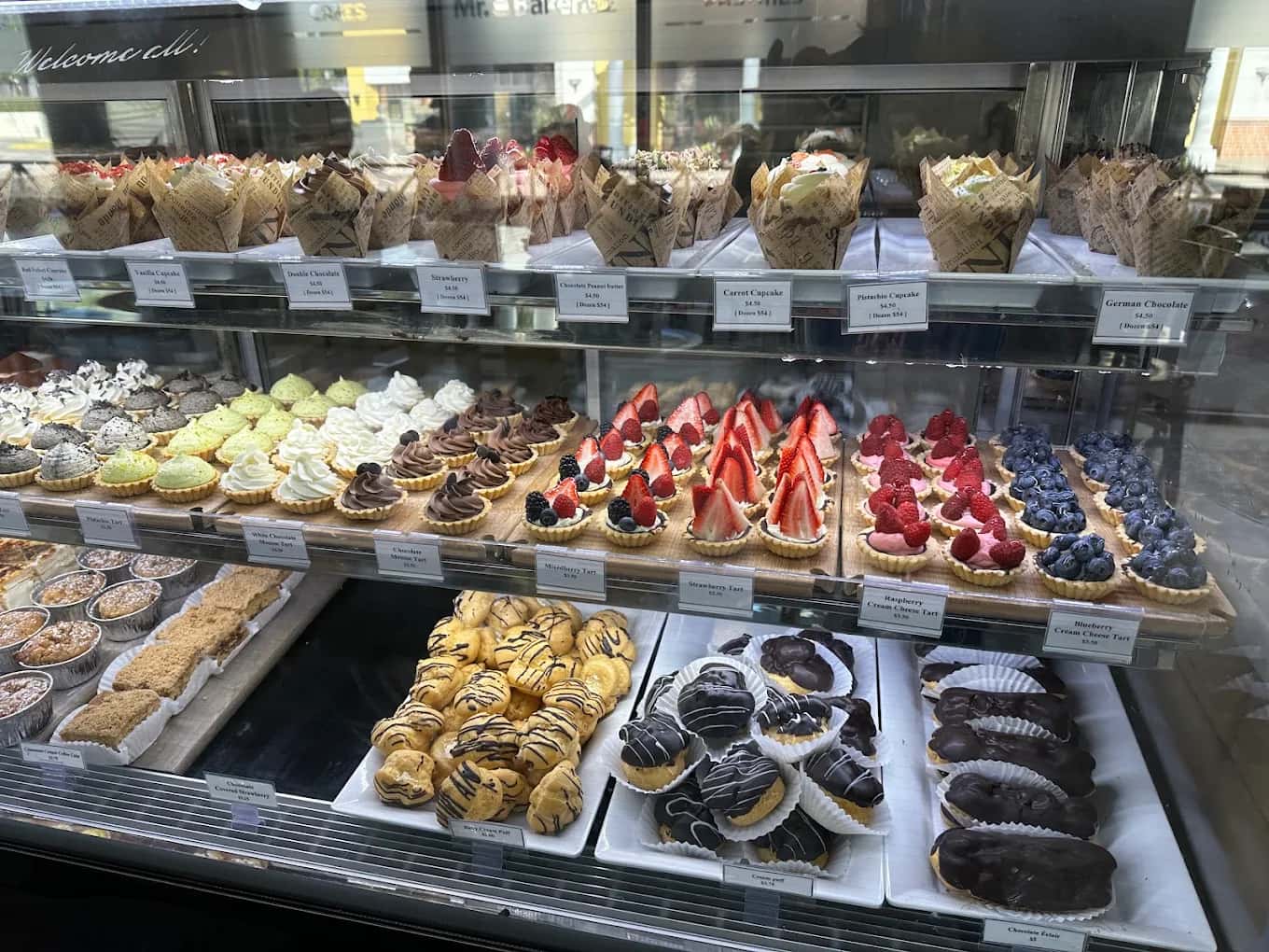 Display case of cupcakes, fruit tarts, cream puffs and eclairs at Mr. Baker Bakery & Cafe