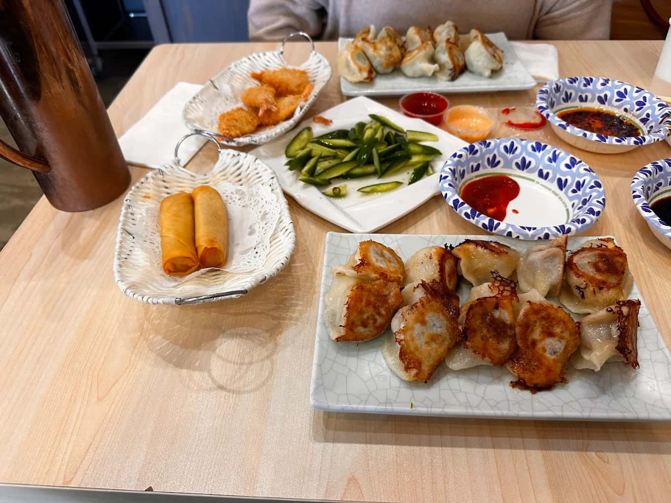 Pan-fried dumplings, spring rolls, fried shrimp and cucumber salad on a table at Mr Dumpling