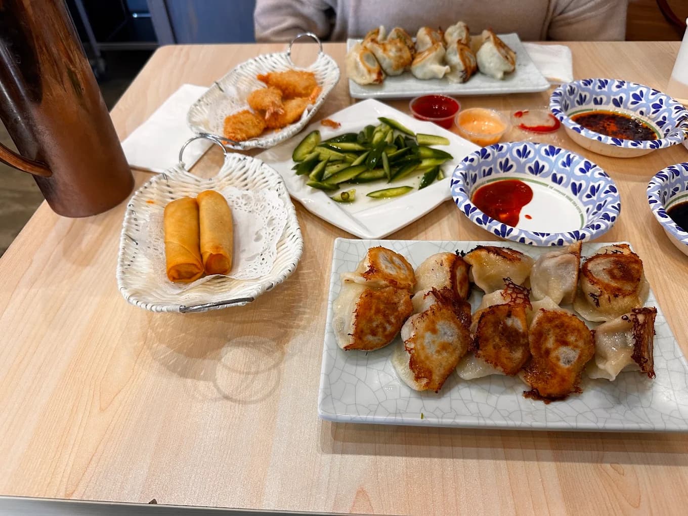 Pan-fried dumplings, spring rolls, fried shrimp and cucumber salad on a table at Mr Dumpling