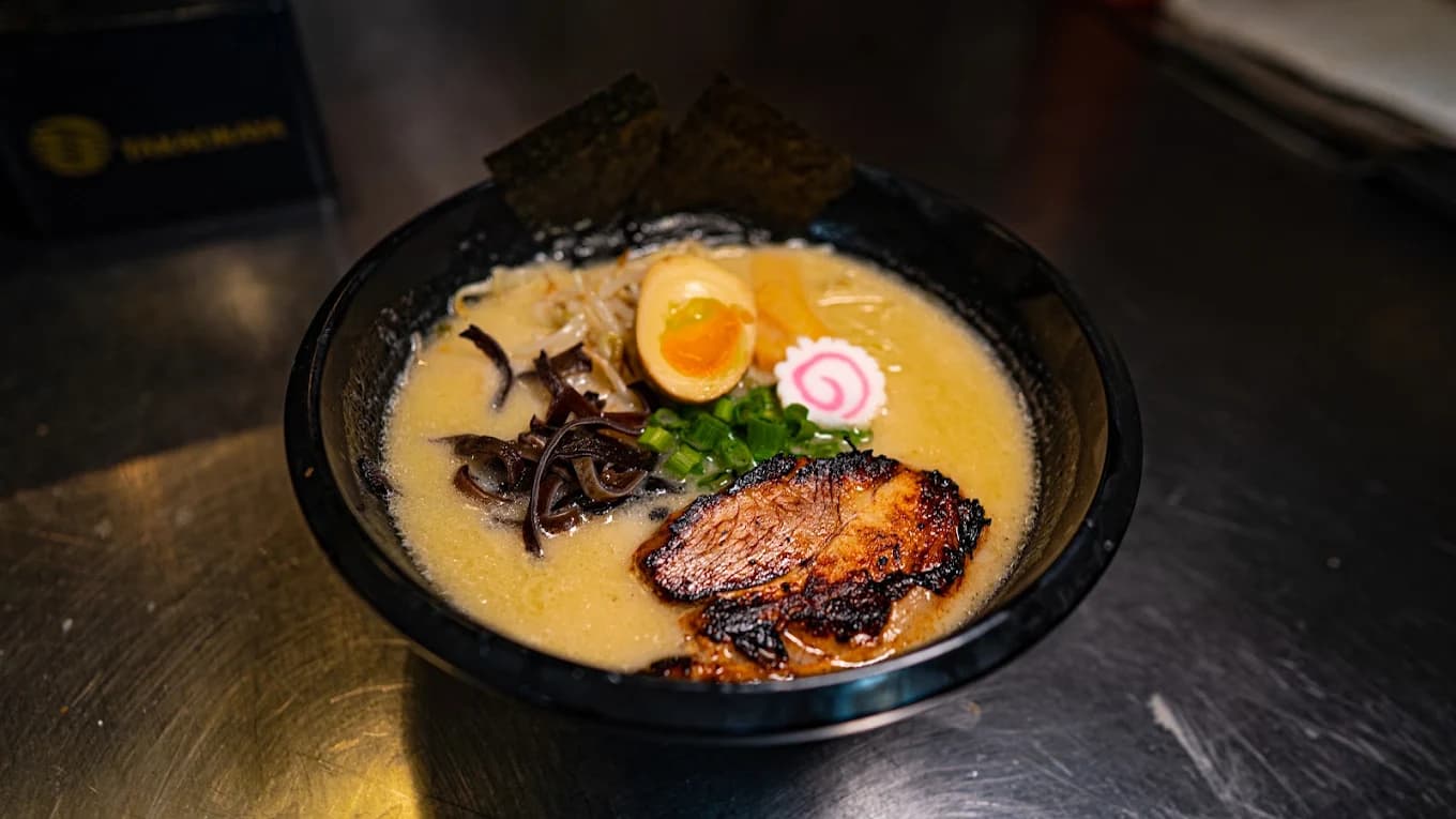 Bowl of ramen at Noods Bar with chashu, soft-boiled egg, fish cake, nori and scallions