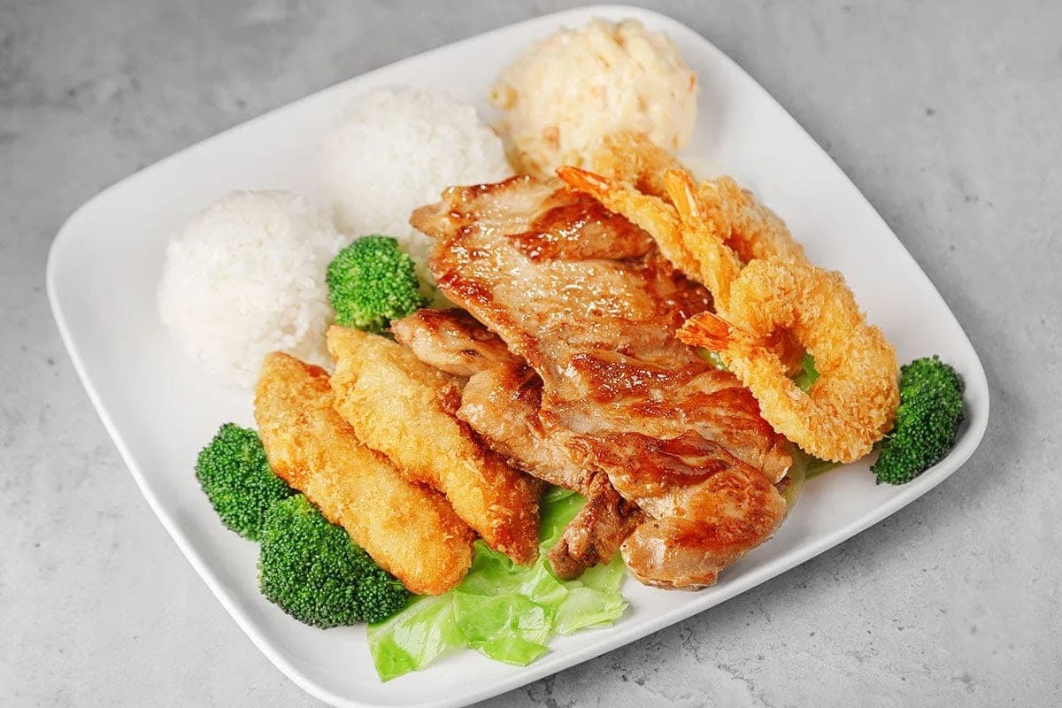 A plate of grilled chicken, fried fish and tempura shrimp with two scoops of rice, macaroni salad and broccoli